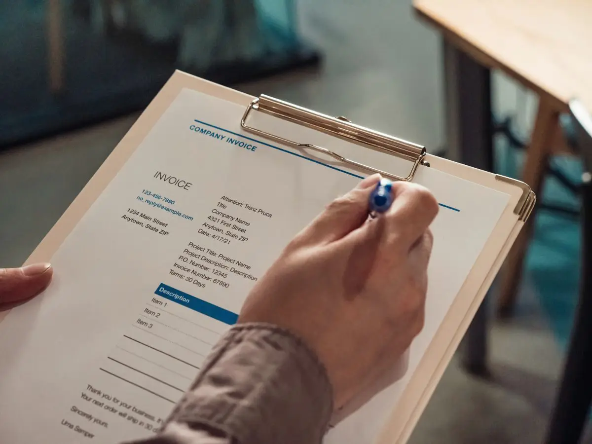 Hand holding an invoice on a clipboard