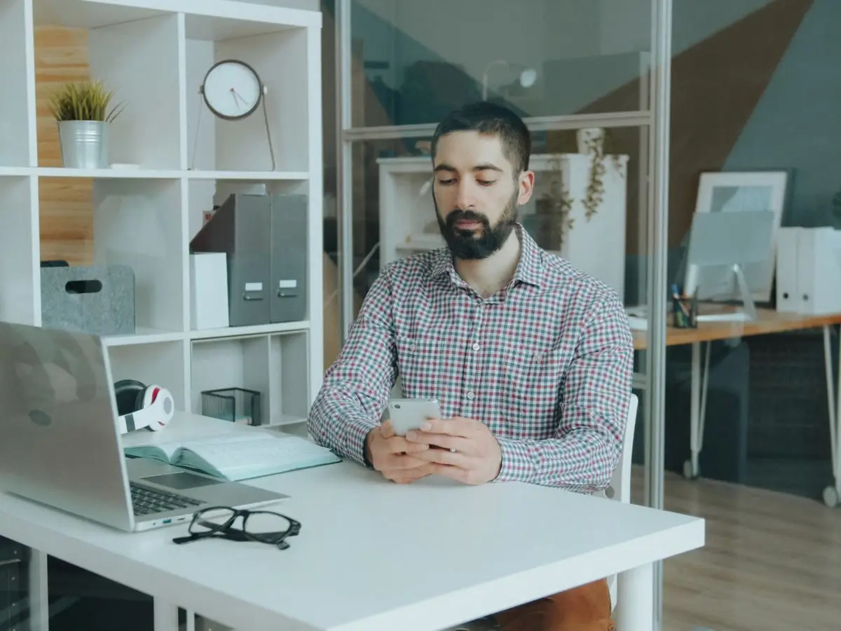Man checking his phone at an office desk