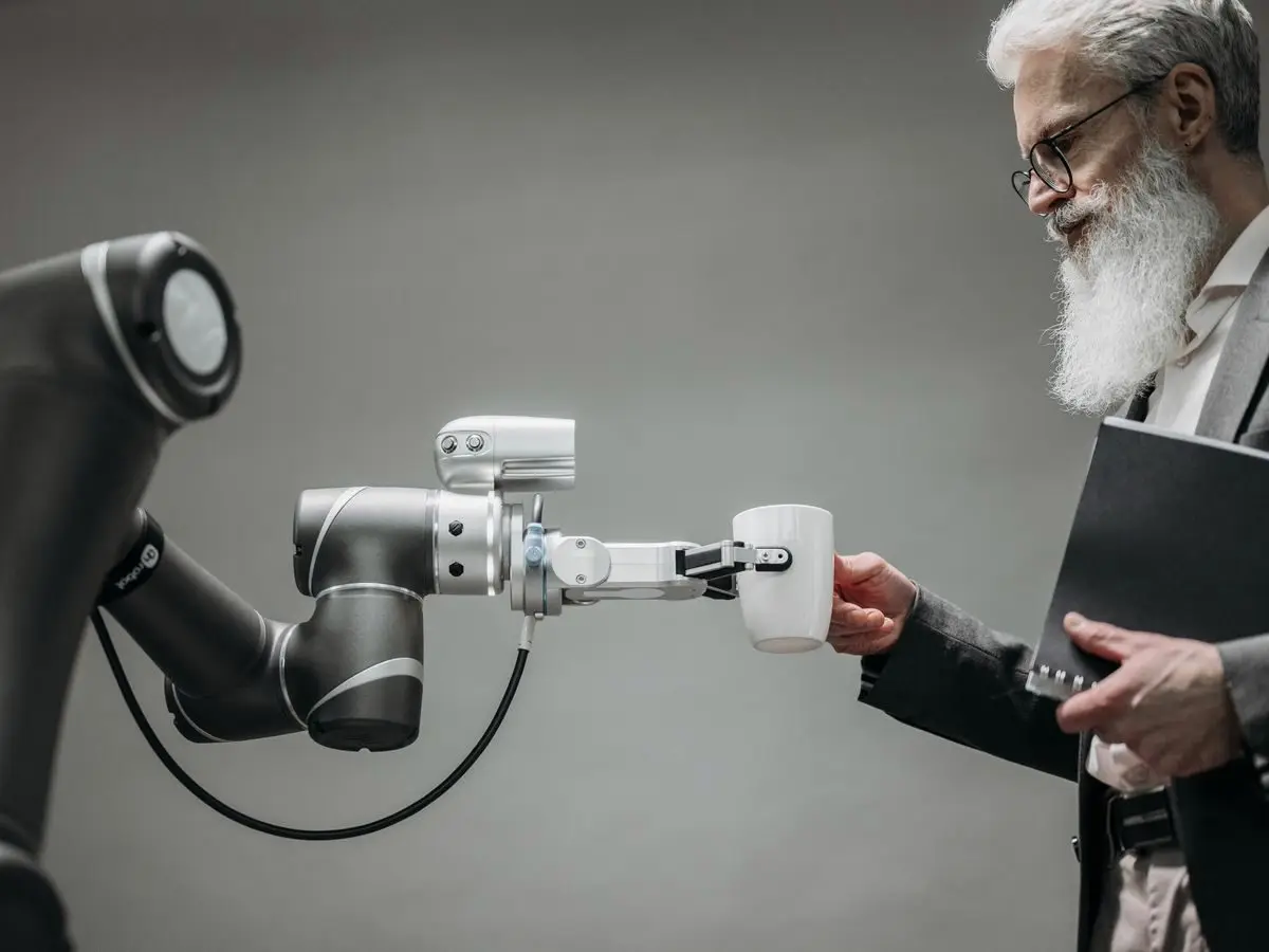Robotic arm handing a cup to a businessman