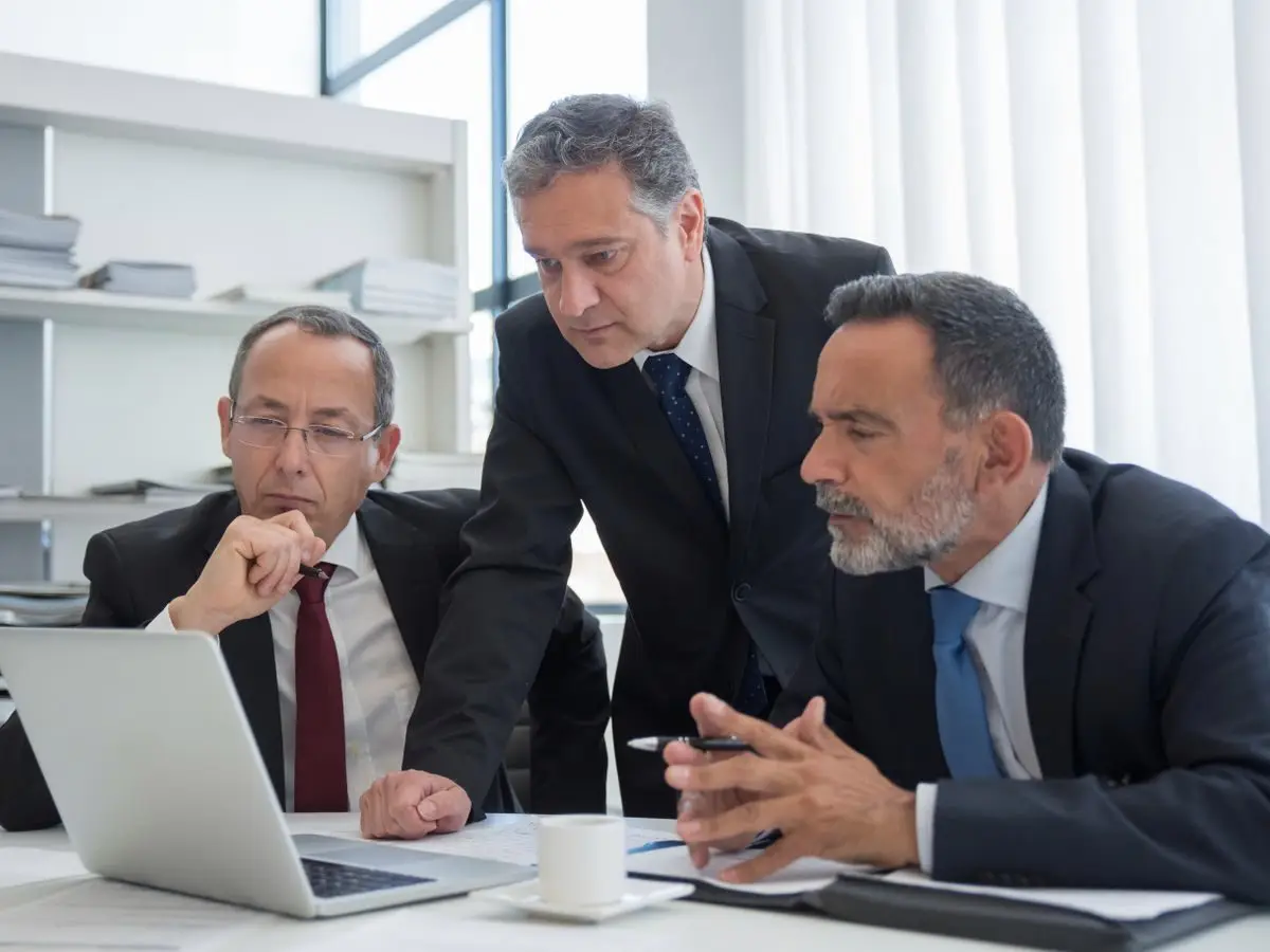 Executives discussing a decision around a laptop