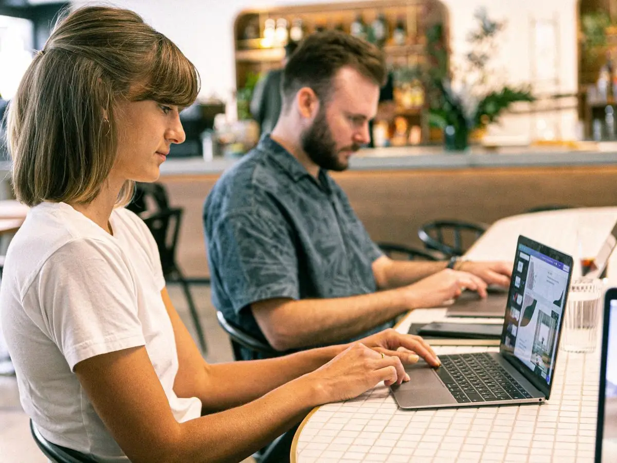 Two professionals working on laptops