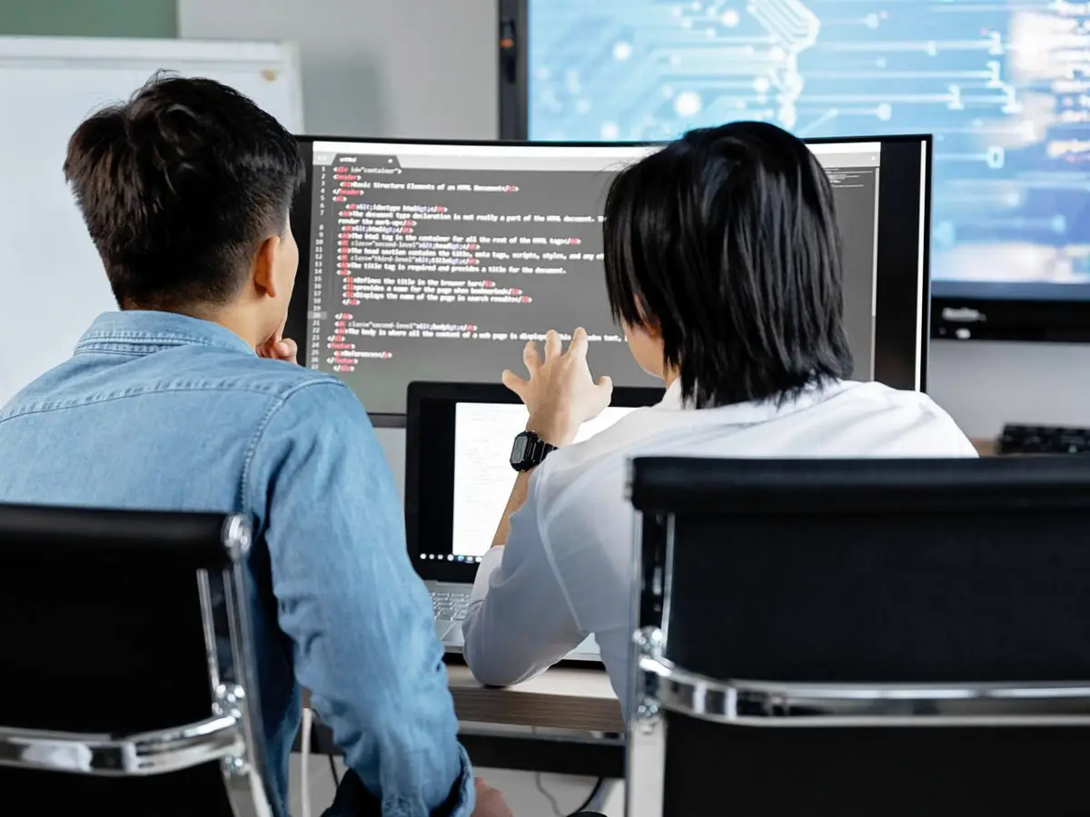 Two developers discussing code on a screen