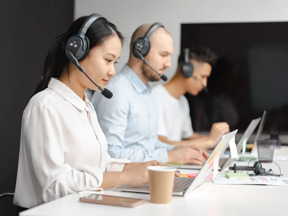 Customer service agents with headsets working at laptops