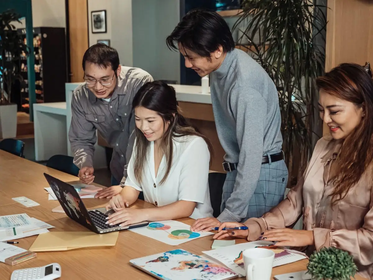 Colleagues collaborating around a laptop