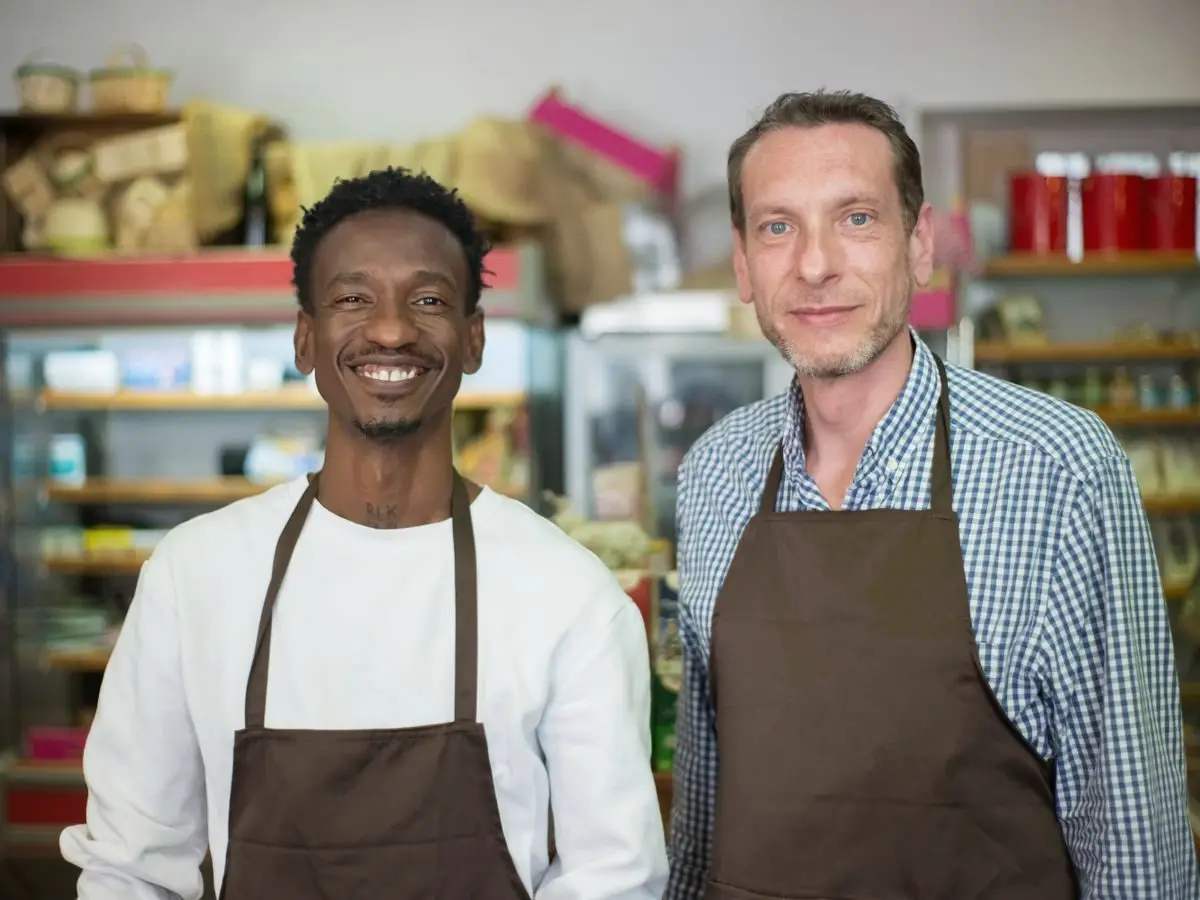 Two smiling store staff in aprons